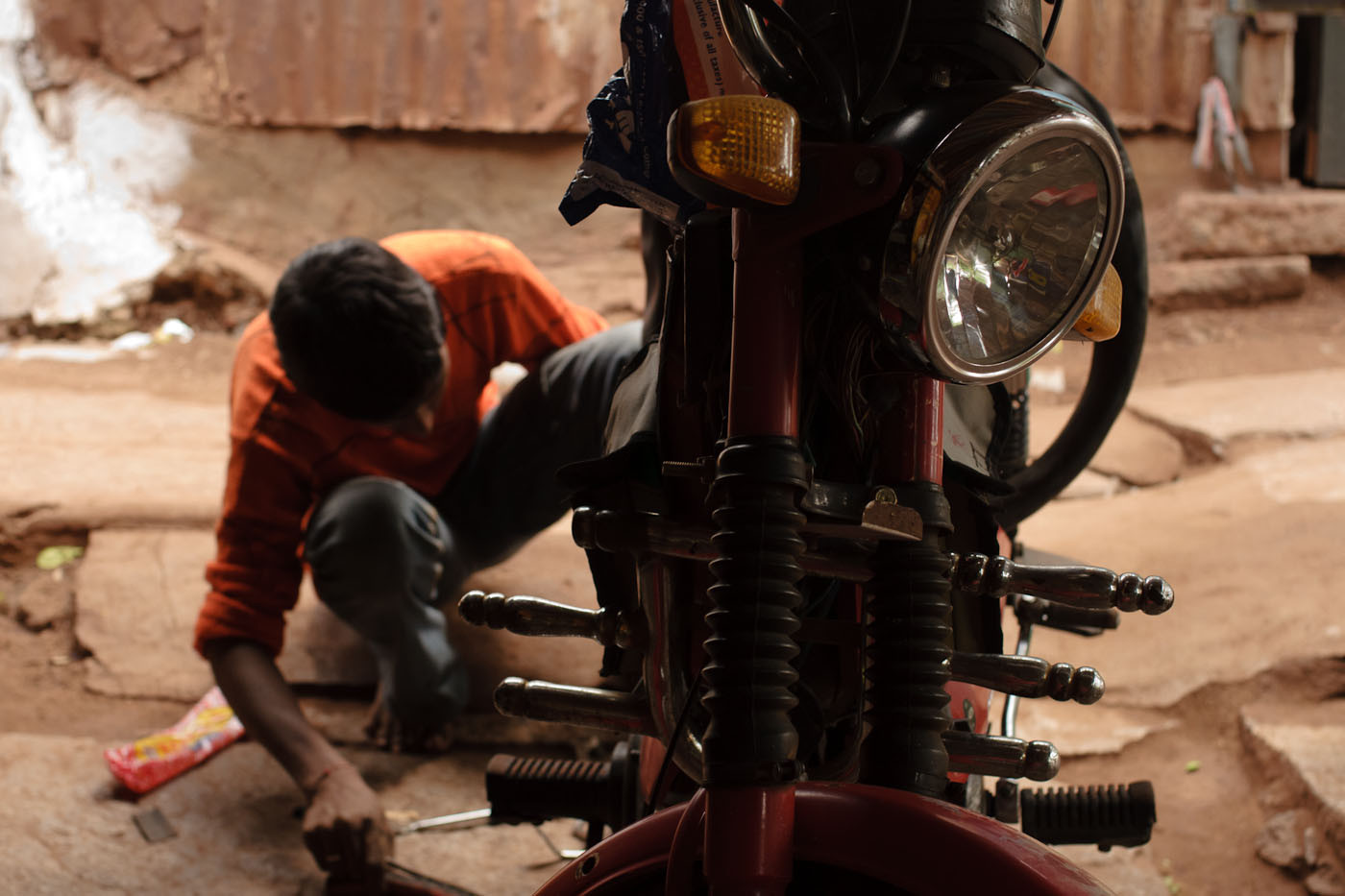 Indian boy fixing a flat tire on a scooter in a bike shop in Hospet, India