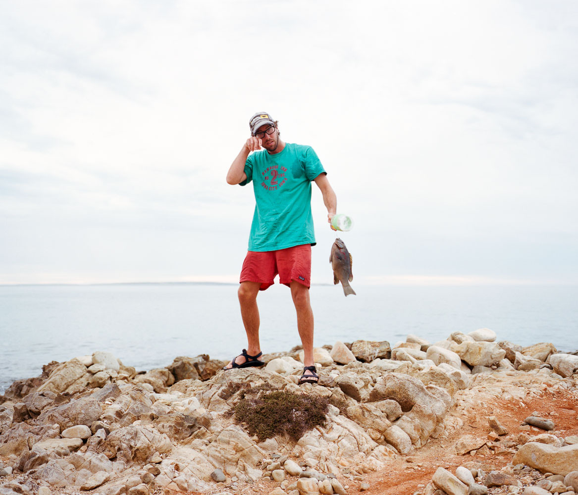 Portrait of a man standing with a fish he caught in Baja, Mexico