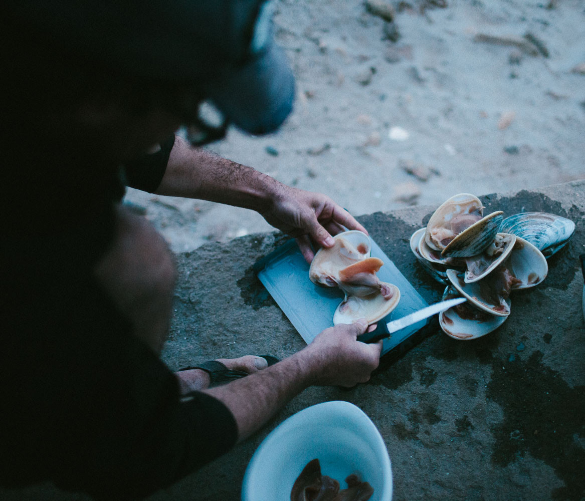 Man cutting up clams on the beach in Baja, Mexico